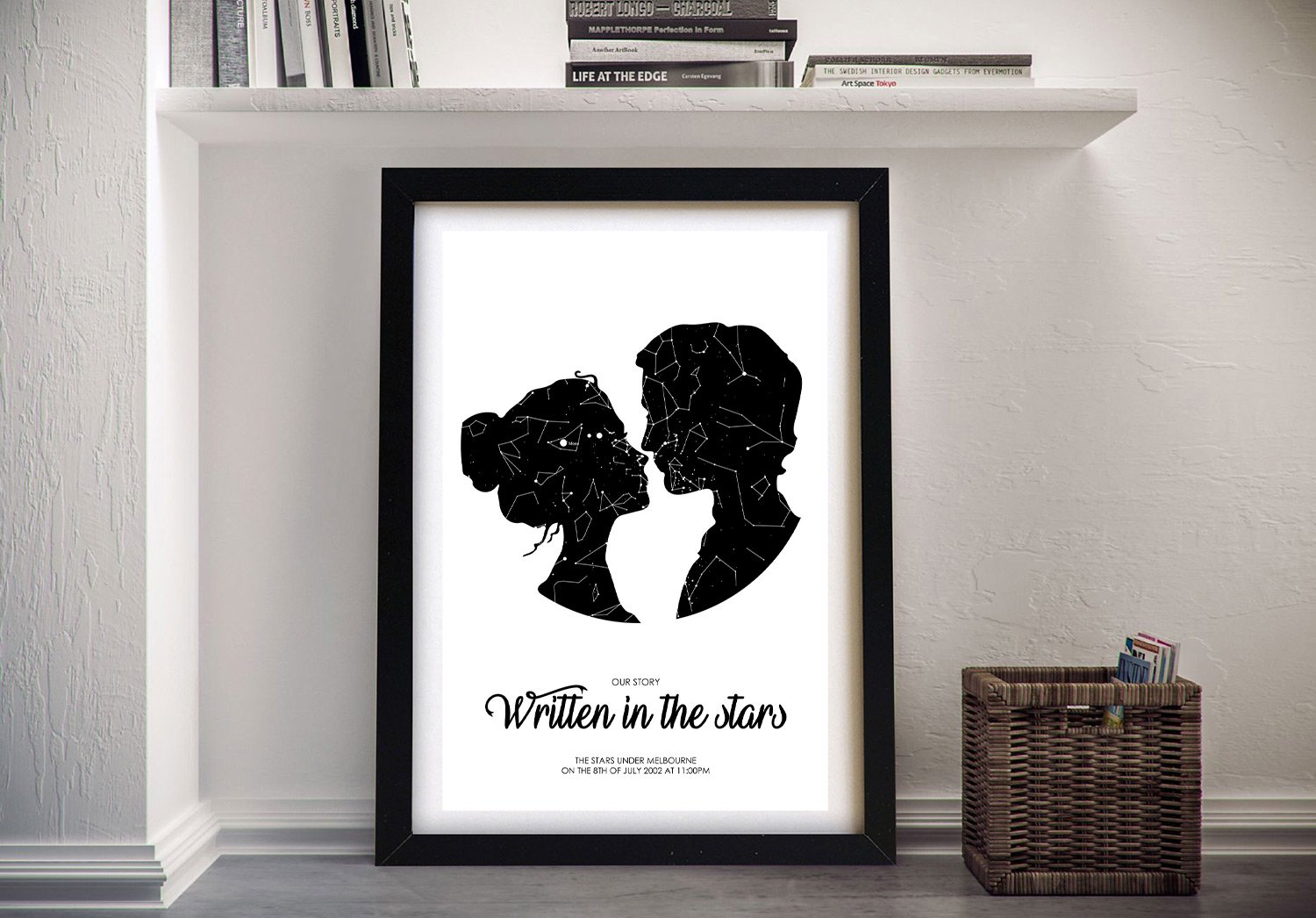 Black-framed romantic silhouette star map propped beside a wicker basket on a soft grey floor